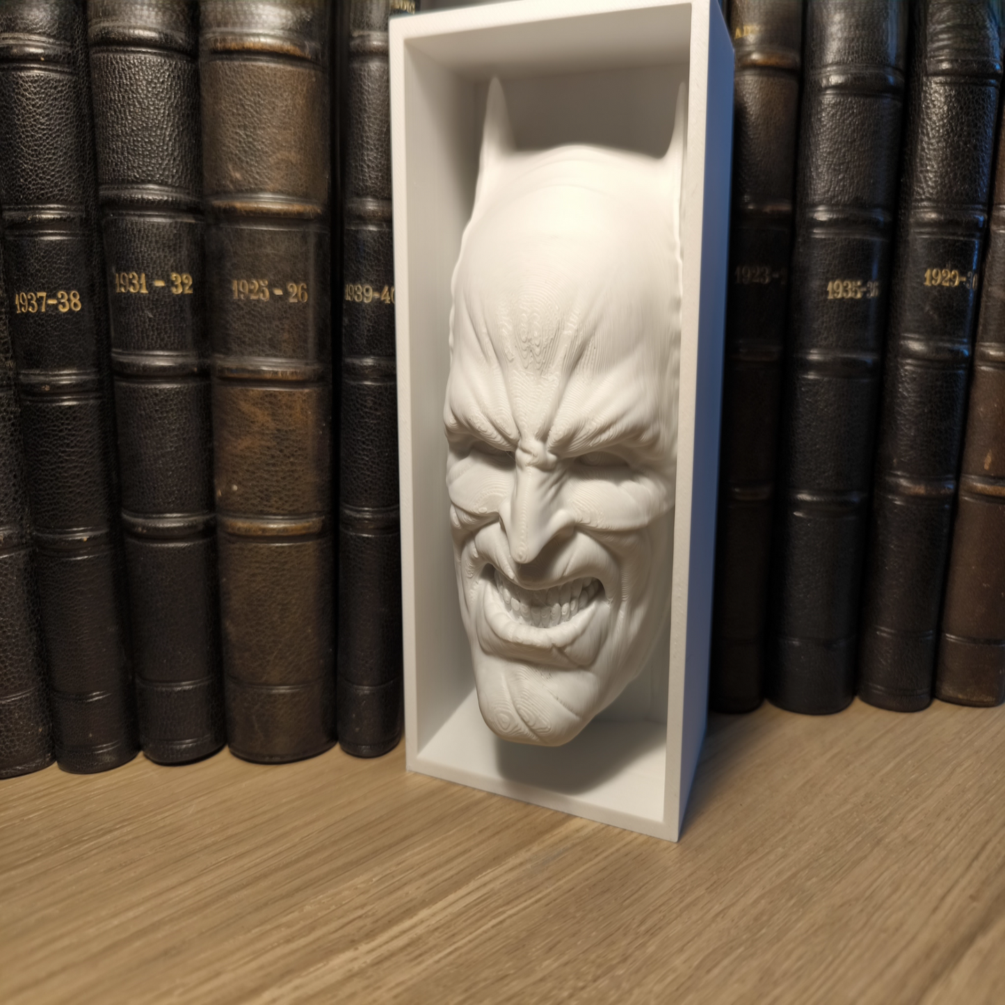 White mask in a box on a wooden surface with books in the background