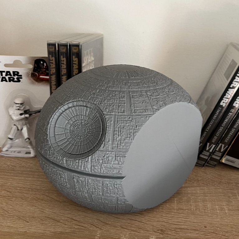 Death Star-shaped object on a wooden surface with Star Wars packaging in the background