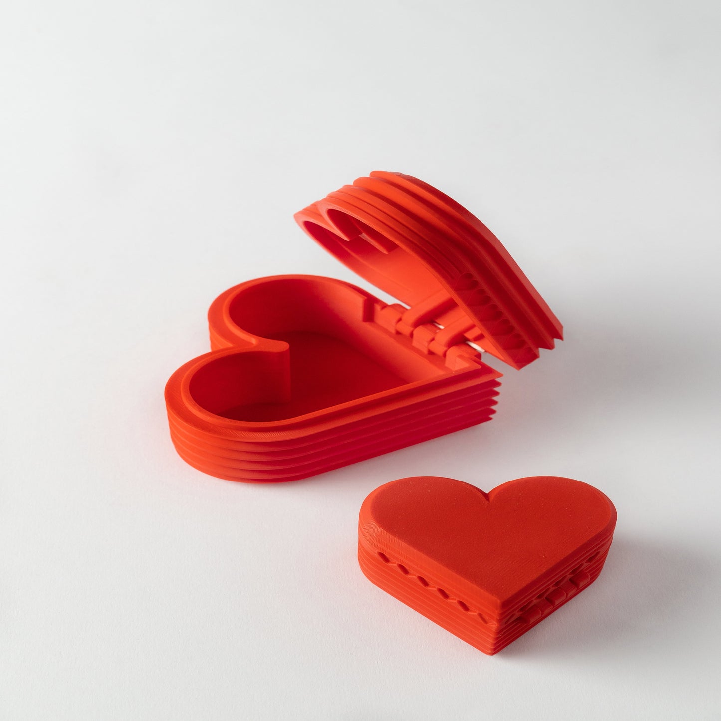 A red heart-shaped 3D printed gift box, open to show its interior.