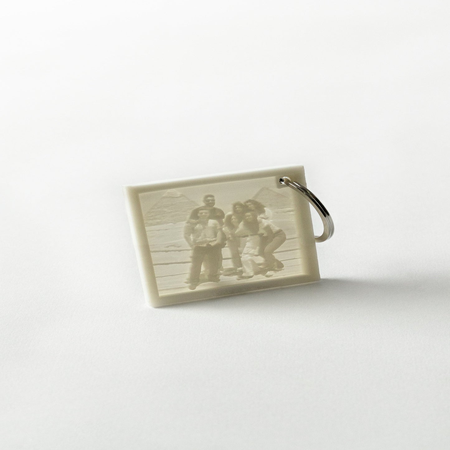 A custom lithophane keychain with a light-activated photo printed on it, displaying a group of people.