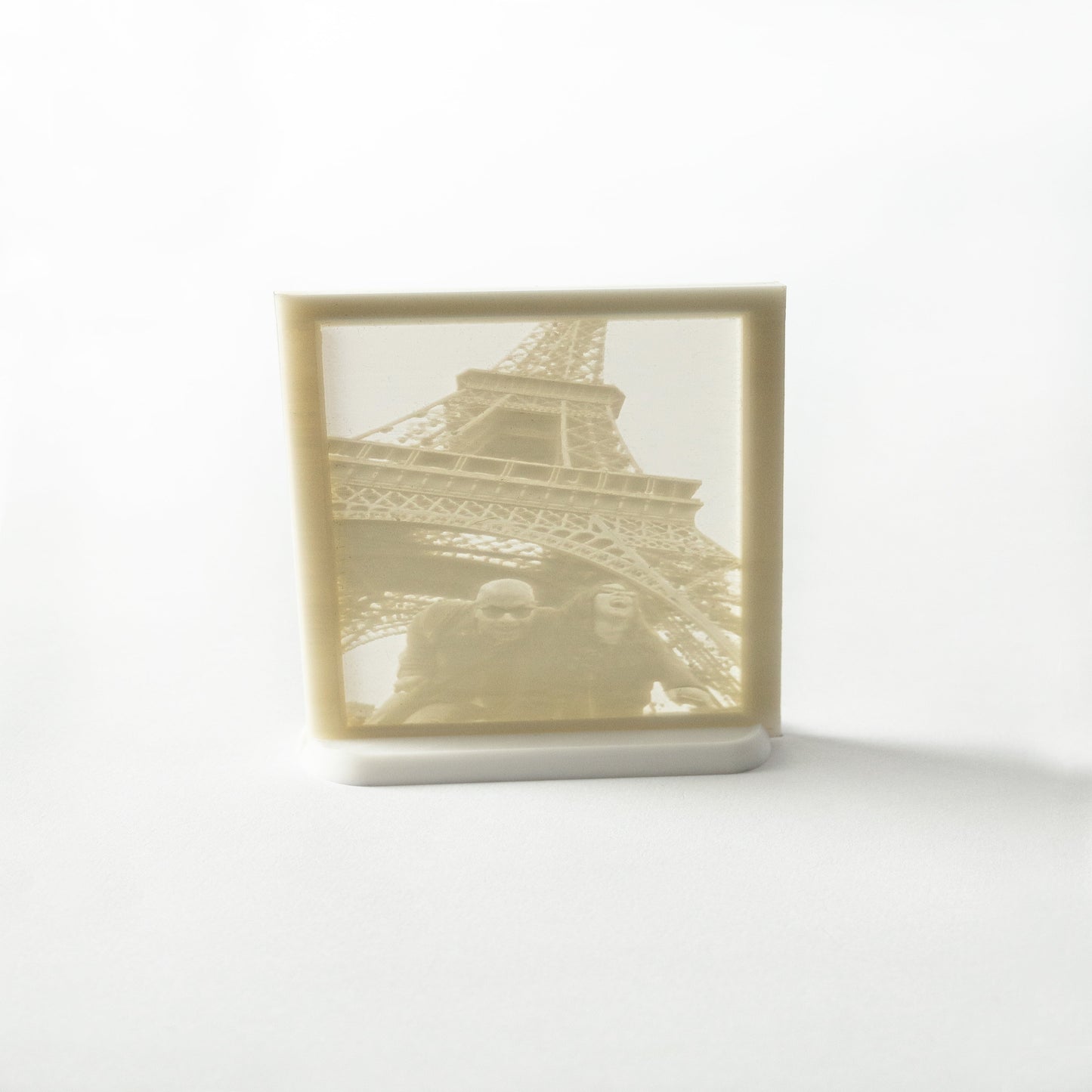 A flat framed light-up photo of the Eiffel Tower, illuminated, showcasing a silhouette of the structure against a lighter background.