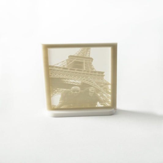 A flat framed light-up photo of the Eiffel Tower, illuminated, showcasing a silhouette of the structure against a lighter background.