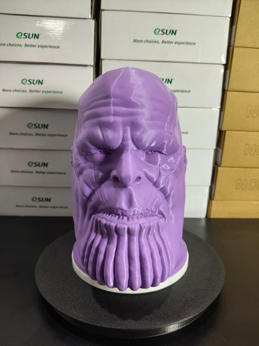 Purple 3D-printed head model on a black stand with boxes in the background