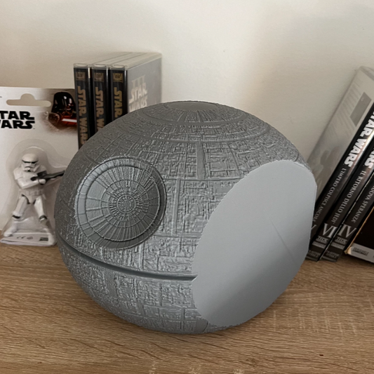 Death Star-shaped object on a wooden surface with Star Wars packaging in the background