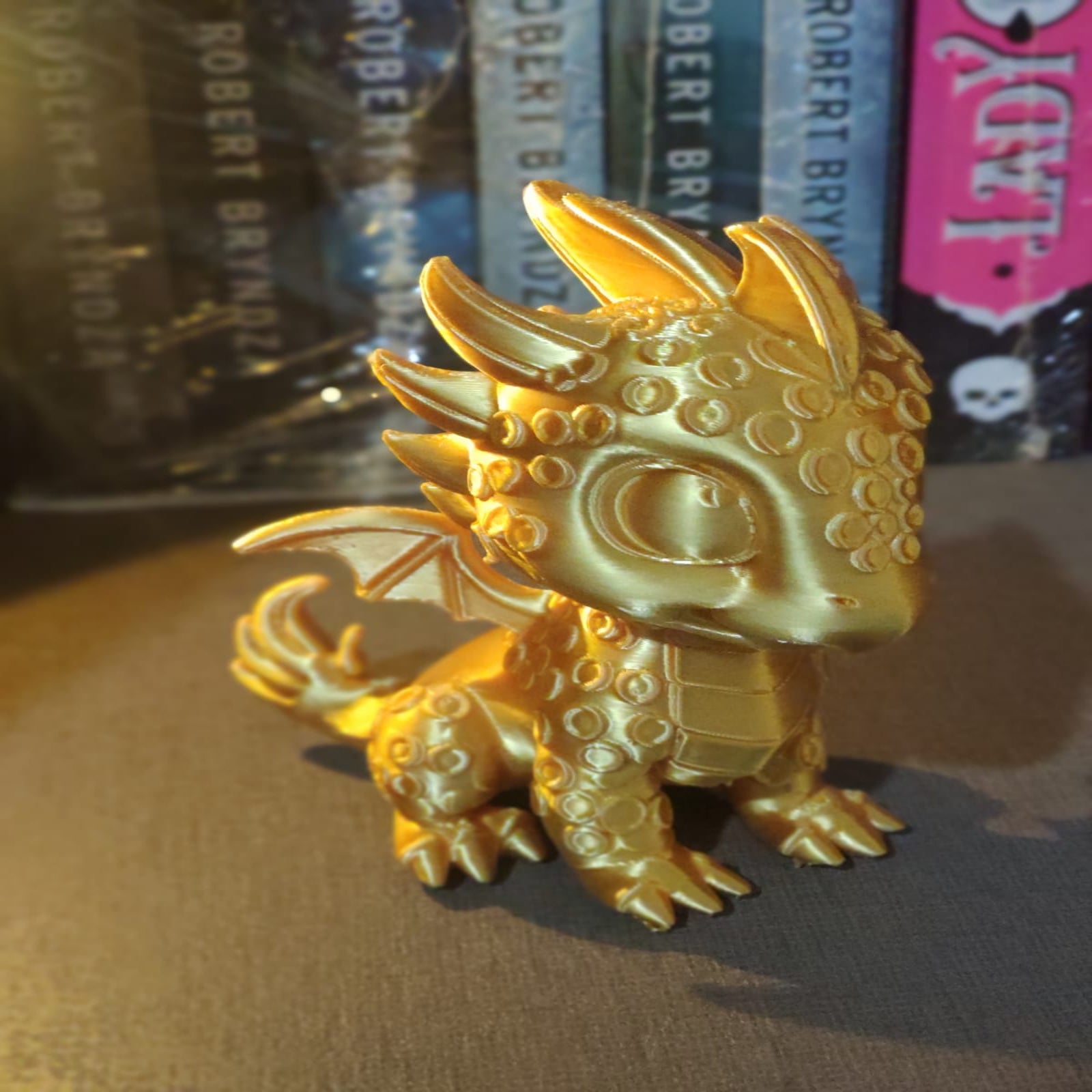 Gold dragon figurine in front of books with visible branding