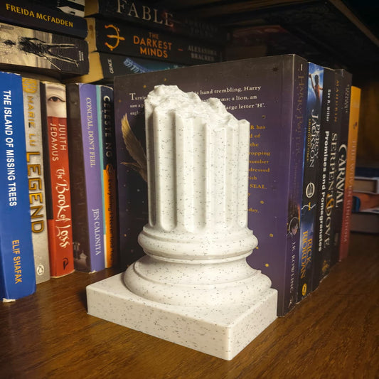 Decorative column sculpture on a bookshelf with books in the background